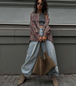 Outdoor street style view of a red plaid button-down shirt paired with oversized denim pants