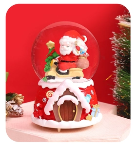 Close-up of a Santa on motorcycle Christmas snow globe with a red cottage base