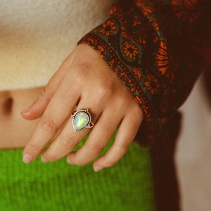 Détail macro d'une bague en argent vintage avec opale en goutte sur une main