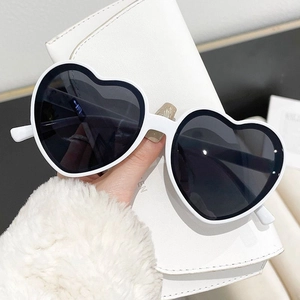 Close-up of white heart-shaped sunglasses with dark lenses and glossy finish