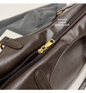 Macro shot of smooth gold-tone zipper and vintage dark brown leather texture on a tote bag