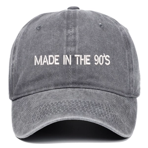 Detail of white Made in the 90's embroidery on washed dark grey cotton baseball cap