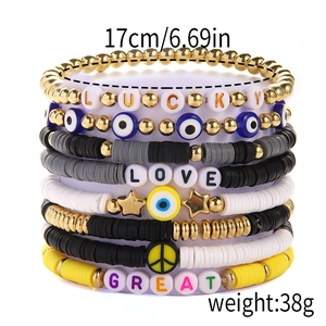 Detail of stacked handmade bracelets featuring polymer clay beads and golden lucky charms
