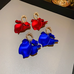 Detail view of matte red and blue flower petal earrings with textured gold metal rings