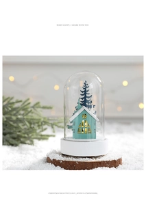 Gros plan d'un dôme en verre avec maison bleue, sapin de Noël et lumières LED chaudes