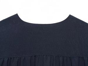 Vue macro du décolleté d'une blouse foncée montrant les coutures et la texture du lin