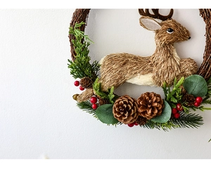Detail of handmade Christmas wreath featuring a natural straw elk with pine cones and berries