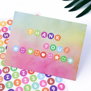 Close-up of colorful letter stickers with a gradient Thank You card and green leaf