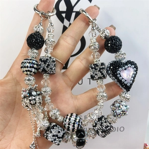 Macro view of handmade black and white beaded charm with heart motif for bags and phones