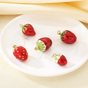 Five red enamel strawberry pendants with gold rings on a white elegance plate