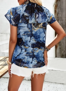 Détail de la blouse imprimé marbre bleu et or avec boutons au dos et manches à volants