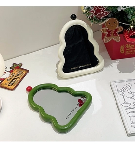 Detail of Christmas-themed cream wavy mirrors with Merry Christmas text on a festive desk
