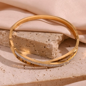 Macro detail of gold-plated crossover bracelet with Roman numerals and crystals