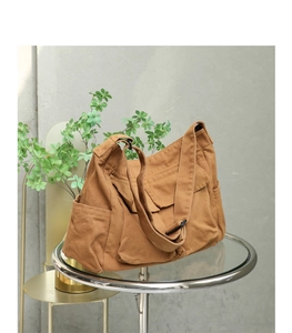 Close-up of vintage brown washed canvas messenger bag on a sleek glass tabletop