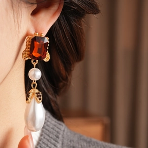 Detail view of vintage drop earrings with red gemstone and pearls on female model