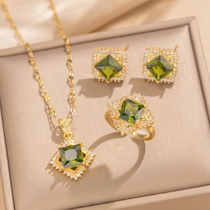 Elegant gold jewelry set with green square gems in a beige gift box display