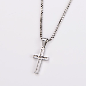 Macro detail of silver stainless steel cross pendant featuring JESUS engraving and box chain