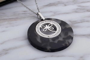 Detail of dragonfly pendant necklace with crystal border on marble background