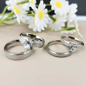 Detailed view of titanium steel couple rings with frosted finish and sparkling zircon
