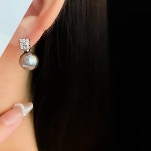 Macro shot of an elegant dark grey pearl earring featuring a square zircon cluster setting