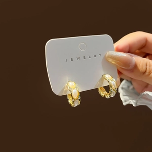 Detailed view of vintage gold hoop earrings featuring oval pearls on a jewelry card
