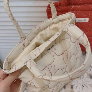 Close-up of heart-shaped quilting and fabric texture on a cream-colored tote bag