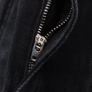 Vue macro détaillée de la fermeture éclair métallique YKK sur un jean denim noir