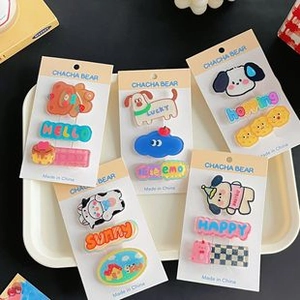 Detail view of 5 sets of cute acrylic hair clips featuring cartoon animal designs and text