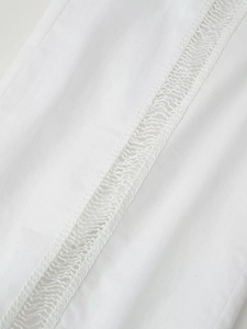 Détail du pantalon blanc de style doux montrant la texture du tissu en dentelle ajourée