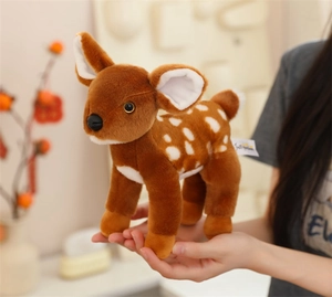 Close-up of a small plush spotted fawn held in hands showing soft texture and detail
