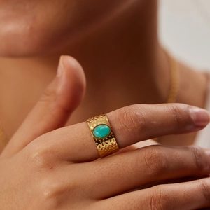 Close-up of hammered gold band ring featuring an oval turquoise stone on model