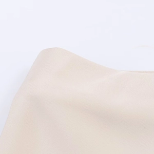 Gros plan sur la texture du tissu en satin beige avec des fibres synthétiques lisses