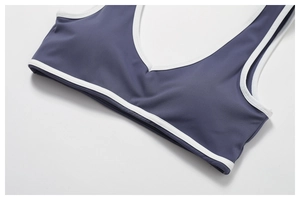 Detail of gray-blue sports bra showing deep V-neckline and white contrast trim stitching