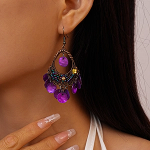 Close-up of Bohemian drop earrings with purple shell sequins worn by a model
