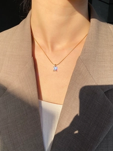 Detail view of a gold titanium necklace featuring a sparkling rectangular zircon pendant