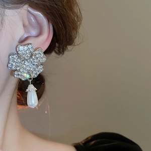 Detail of flower shaped earrings with sparkling rhinestones and teardrop pearl drops