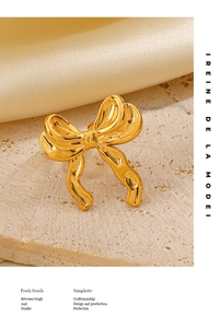 Macro detail of 18K gold plated bow jewelry piece with mirror polished finish on stone surface