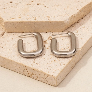U-shaped stainless steel earrings in silver finish displayed on aesthetic beige stones