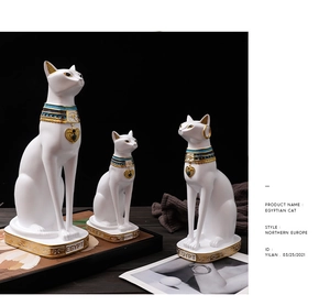 Dettaglio di tre figurine di gatti egizi in bianco e oro con collari decorati