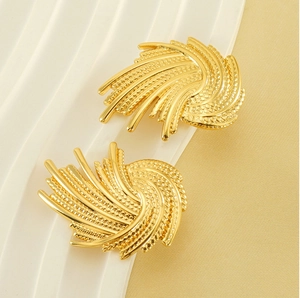 Macro shot of gold spiral woven earrings with radial wing texture and beaded center