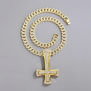 Close-up of golden iced-out Cuban chain and inverted cross pendant with sparkling rhinestones