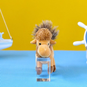 Primo piano di un simpatico portachiavi in peluche a cammello su sfondo blu e giallo
