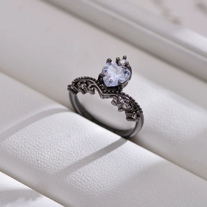 Macro detail of a gothic black ring featuring a heart-shaped gemstone on white leather