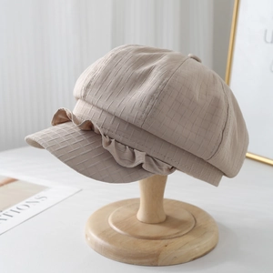 Chic beige linen newsboy cap with elegant ruffled edges and textured fabric on stand
