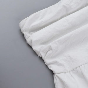 Détail du tissu de robe blanche montrant le design froncé et la texture à volants