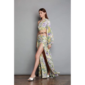 Detail of high-slit floral dress featuring one-shoulder design and gold chain waist link