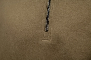 Detailed macro view of olive green cotton fabric texture and half-zip collar stitching