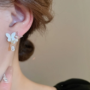 Detail of butterfly earring with pearl, zircon drop and gold finish on model