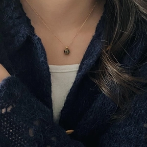 Close-up of a 925 silver golden necklace featuring a round zebra stone pendant on a model