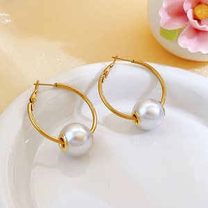 Detail view of elegant gold-plated hoop earrings with large white round pearls